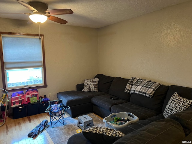 living room featuring light hardwood / wood-style floors, a textured ceiling, and ceiling fan