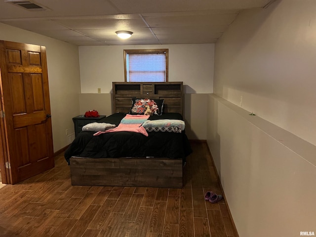 bedroom with dark wood-type flooring and a paneled ceiling