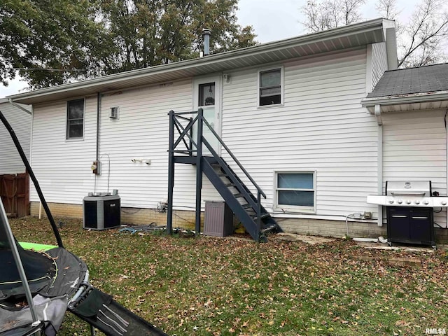 rear view of house featuring central air condition unit and a yard