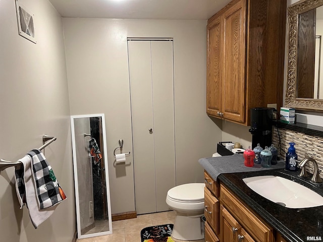 bathroom with toilet, vanity, tasteful backsplash, and tile patterned floors