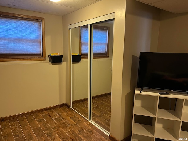 unfurnished bedroom featuring dark wood-type flooring, a paneled ceiling, and a closet