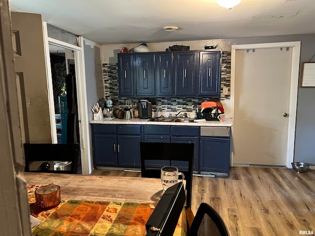 kitchen featuring blue cabinetry, decorative backsplash, light hardwood / wood-style flooring, and sink