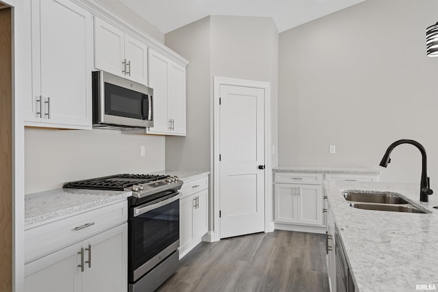 kitchen with white cabinetry, sink, light stone counters, and appliances with stainless steel finishes