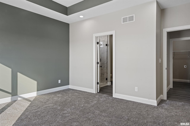interior space featuring ensuite bathroom and dark colored carpet