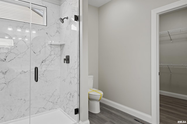 bathroom featuring wood-type flooring, toilet, and a shower with door