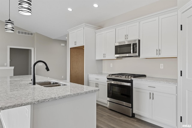 kitchen with appliances with stainless steel finishes, white cabinetry, sink, hanging light fixtures, and light stone countertops