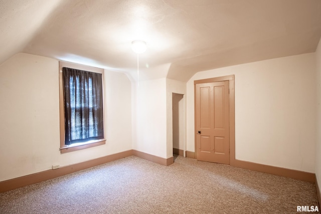 additional living space with carpet flooring, lofted ceiling, and a textured ceiling