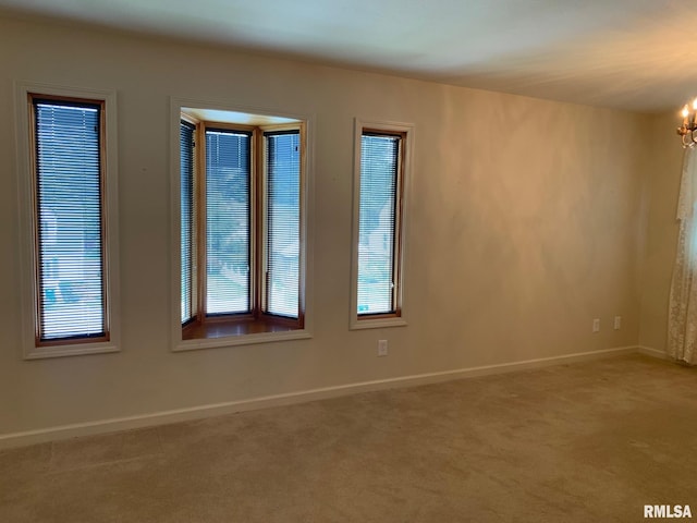 unfurnished room with carpet floors and a chandelier