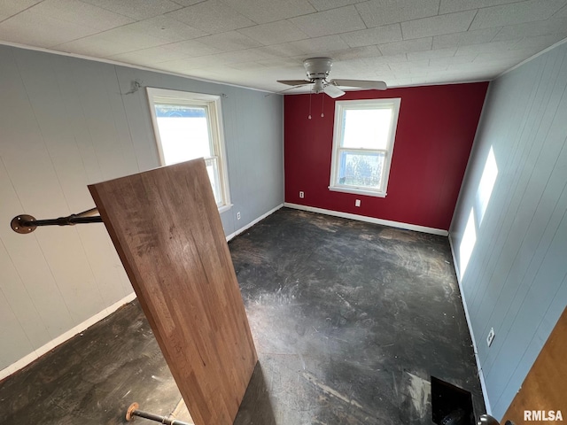 spare room featuring plenty of natural light, wooden walls, and ceiling fan