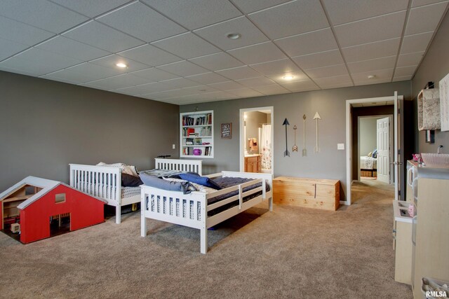 bedroom with a drop ceiling, carpet, and connected bathroom