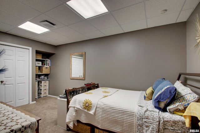 carpeted bedroom featuring a closet and a paneled ceiling