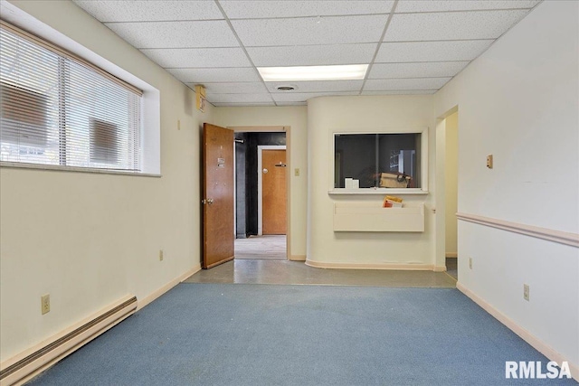 empty room featuring a baseboard heating unit and a drop ceiling