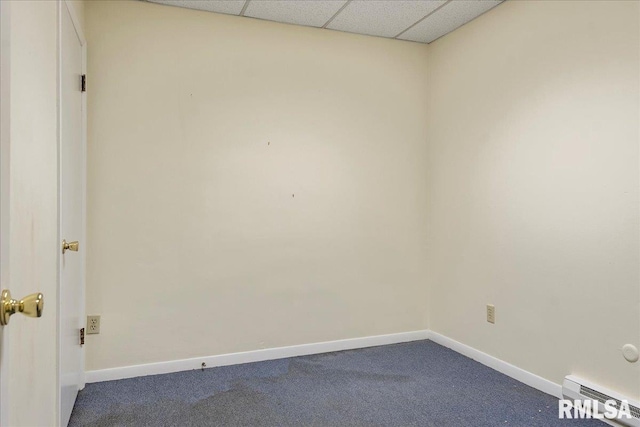 spare room with a paneled ceiling, carpet floors, and a baseboard heating unit