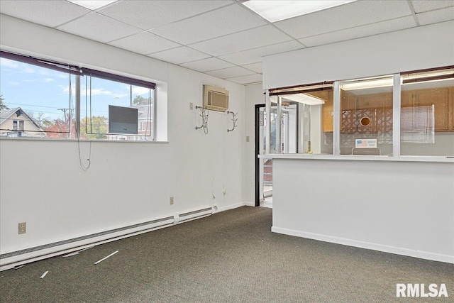 carpeted spare room with a wall unit AC, a baseboard radiator, and a paneled ceiling