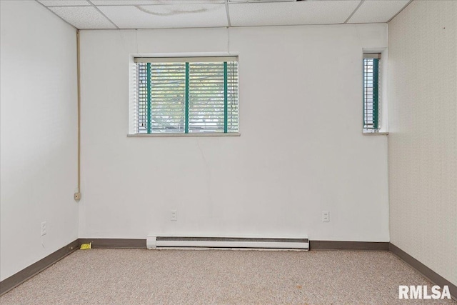 carpeted empty room with a baseboard radiator and a paneled ceiling