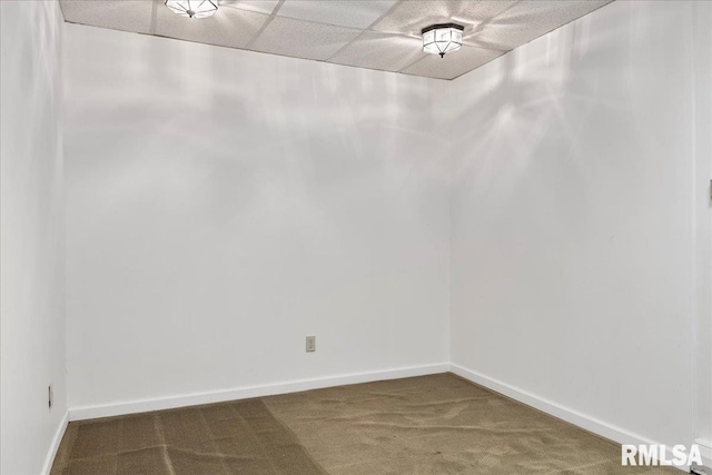 spare room with a paneled ceiling and dark carpet