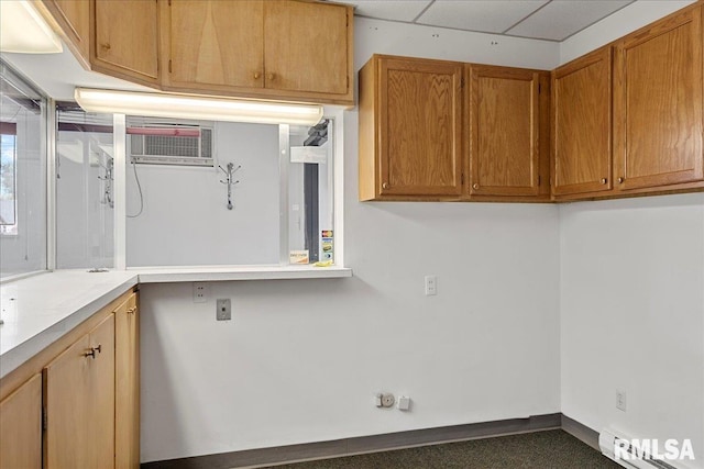 laundry area with an AC wall unit and baseboard heating