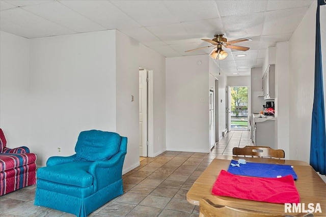 tiled living room with a paneled ceiling and ceiling fan