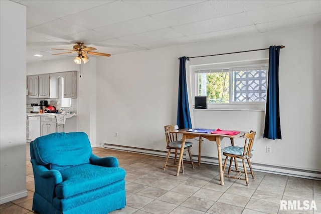 sitting room featuring a drop ceiling, light tile patterned floors, ceiling fan, and a baseboard heating unit