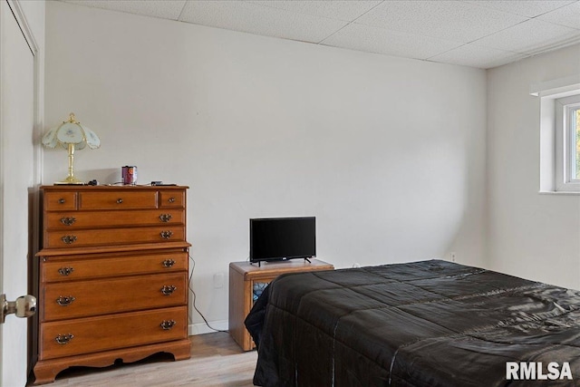 bedroom with light hardwood / wood-style floors and a drop ceiling