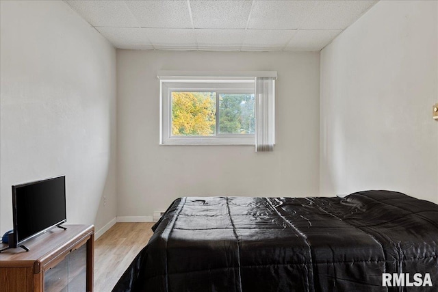 bedroom with light wood-type flooring and a paneled ceiling