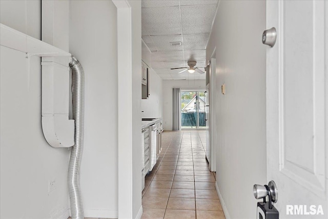 hallway featuring a drop ceiling and light tile patterned flooring