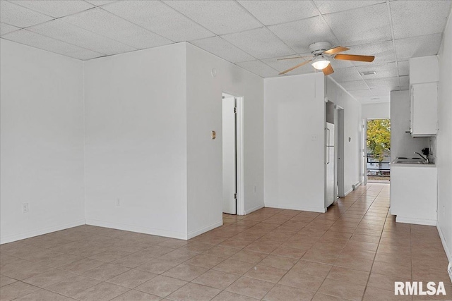 unfurnished room with a paneled ceiling, ceiling fan, sink, and light tile patterned floors