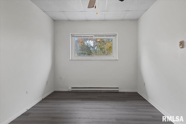 spare room with dark wood-type flooring, a drop ceiling, ceiling fan, and a baseboard radiator