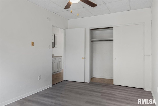 unfurnished bedroom featuring a paneled ceiling, hardwood / wood-style flooring, and ceiling fan