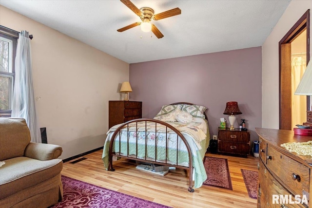 bedroom with a textured ceiling, light hardwood / wood-style flooring, and ceiling fan