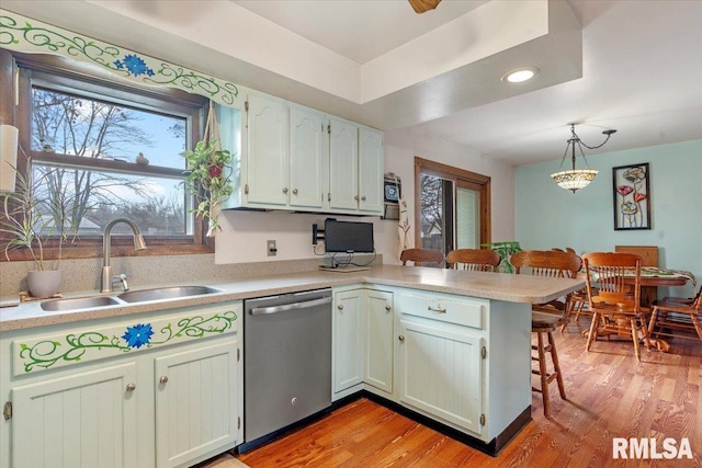 kitchen featuring pendant lighting, dishwasher, sink, light wood-type flooring, and kitchen peninsula