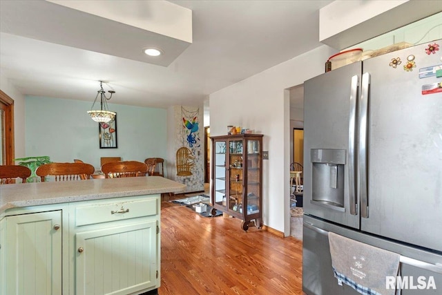 kitchen with decorative light fixtures, stainless steel fridge, green cabinetry, and light hardwood / wood-style flooring