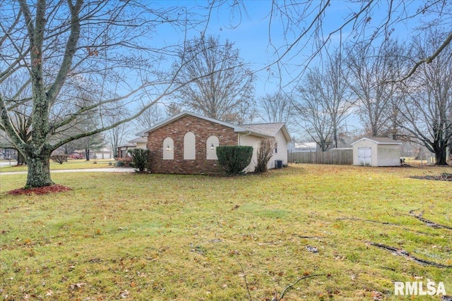 view of side of home with a lawn, central AC unit, and a storage shed