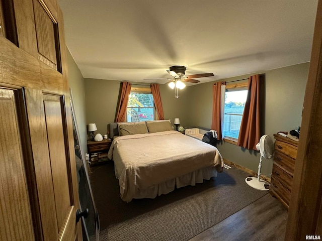 bedroom with dark hardwood / wood-style floors, ceiling fan, and multiple windows