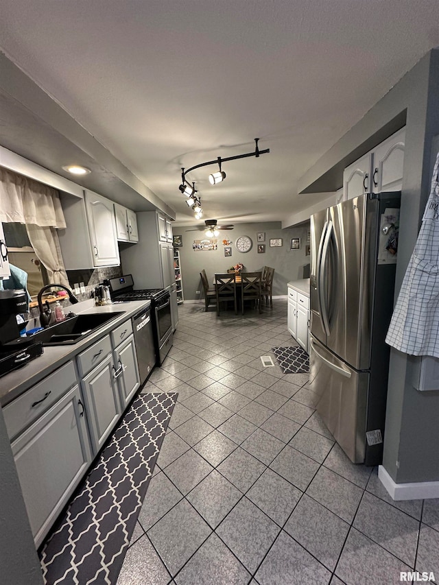 kitchen featuring stainless steel appliances, tile patterned flooring, sink, ceiling fan, and white cabinetry