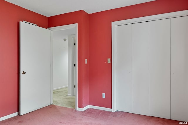 unfurnished bedroom featuring a closet and light colored carpet