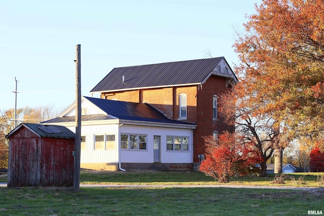 rear view of property featuring a storage shed and a yard