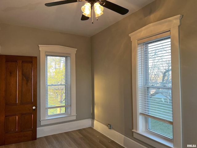 spare room with ceiling fan, a healthy amount of sunlight, and dark wood-type flooring