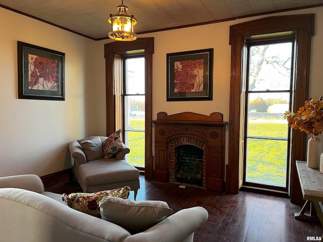 living room with plenty of natural light, dark hardwood / wood-style floors, ornamental molding, and a brick fireplace