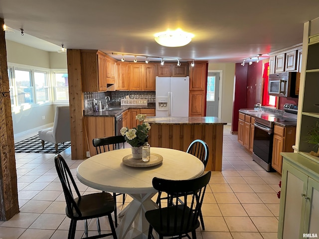 kitchen featuring sink, stainless steel appliances, light tile patterned floors, decorative backsplash, and a kitchen island