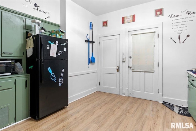 kitchen featuring black refrigerator, green cabinetry, and light wood-type flooring