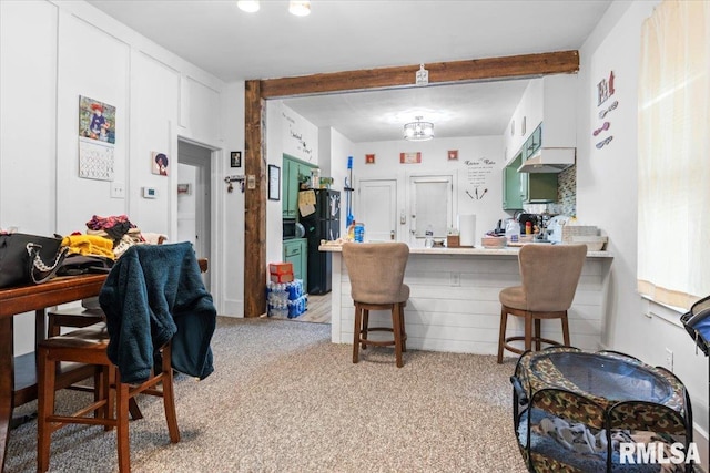 kitchen with kitchen peninsula, black fridge, a breakfast bar, light colored carpet, and white cabinets