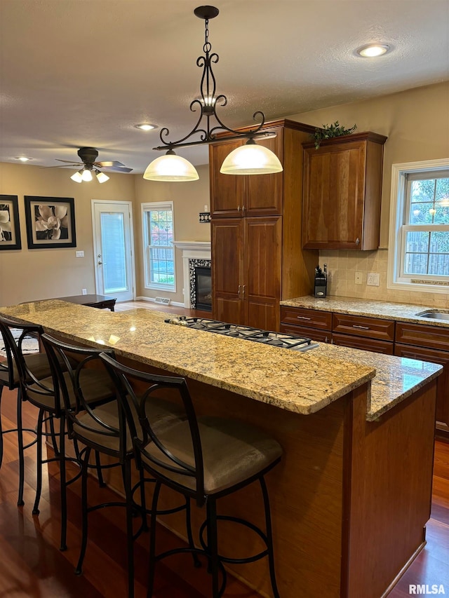 kitchen featuring hanging light fixtures, a kitchen bar, dark wood-type flooring, and a center island
