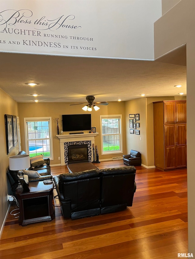living room with a fireplace, wood-type flooring, and ceiling fan
