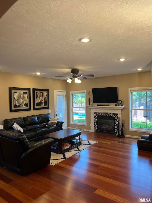 living room with a fireplace, a wealth of natural light, a textured ceiling, and hardwood / wood-style flooring