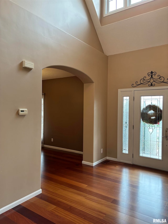 entrance foyer with high vaulted ceiling, plenty of natural light, and dark hardwood / wood-style flooring