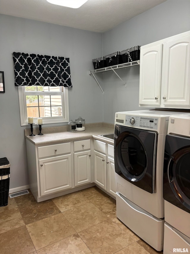 clothes washing area featuring cabinets and washing machine and clothes dryer