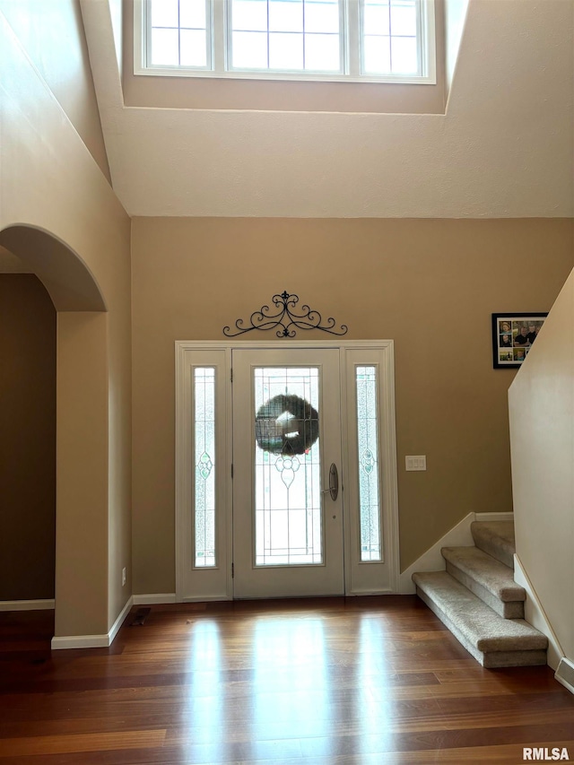 entryway with high vaulted ceiling, a wealth of natural light, and hardwood / wood-style flooring