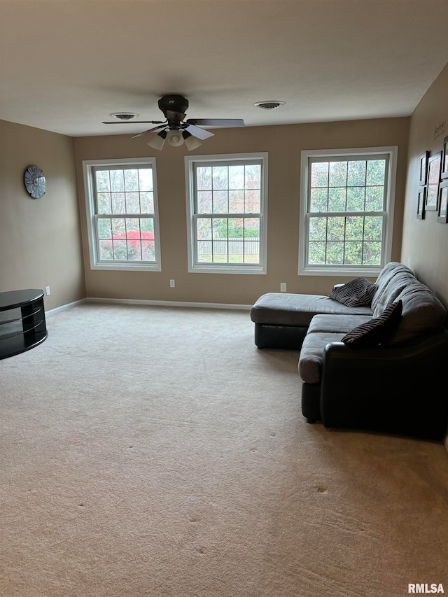 living room with a wealth of natural light, light carpet, and ceiling fan