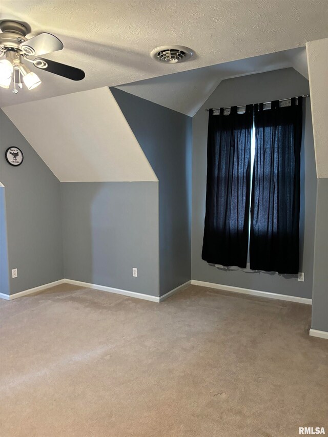 additional living space with ceiling fan, a textured ceiling, light carpet, and lofted ceiling